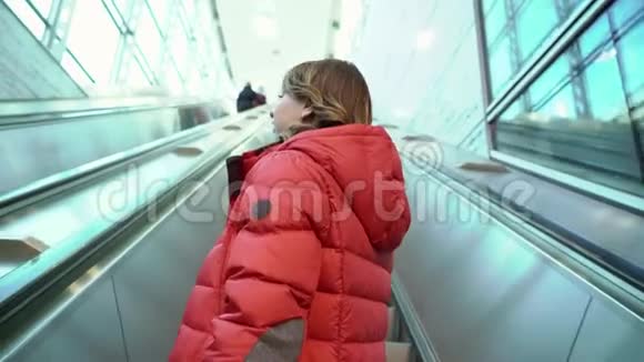 提着手提箱走上自动扶梯的年轻女子视频的预览图