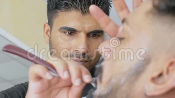 理发店的理发师给他的客户刮脸视频的预览图