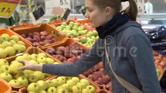 美丽迷人的年轻女人在超市里摘苹果水果健康的饮食观念视频的预览图