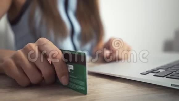 网上购物概念女人手拿着信用卡用笔记本电脑女人的手敲桌子上的卡片视频的预览图