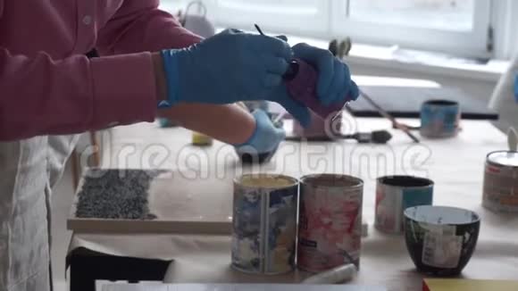 这位艺术家把画笔浸入一罐颜料中艺术工作室视频的预览图