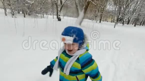 快乐的小男孩在冬天在公园里跑步快乐的男孩在雪地冬季公园玩得很开心微笑软焦视频的预览图