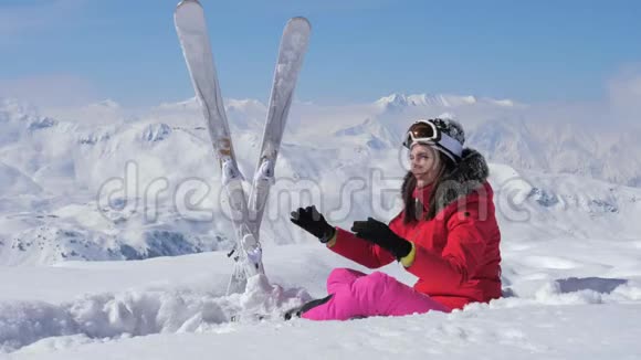 一个美丽的滑雪者在雪地里栖息戴上她的护目镜视频的预览图