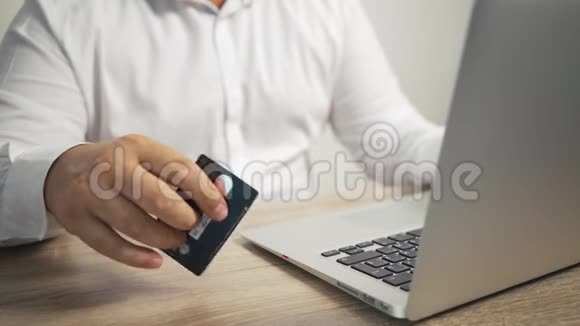 网上购物概念男人手拿信用卡用笔记本电脑男的手敲桌子上的卡片视频的预览图