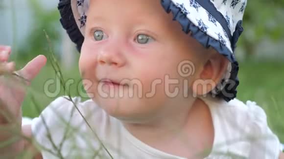 蓝眼睛的小女孩在阳光明媚的夏日里抚摸着绿草视频的预览图