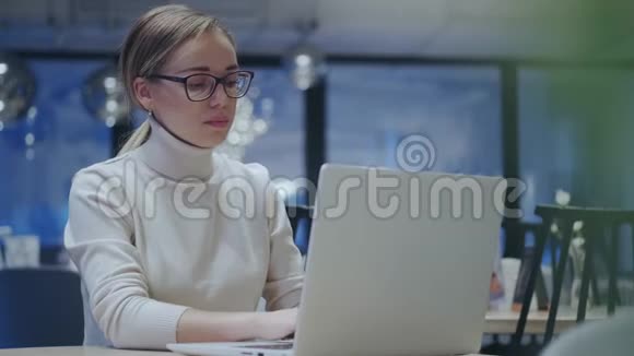 晚上女孩坐在一家舒适的咖啡馆里使用笔记本电脑视频的预览图