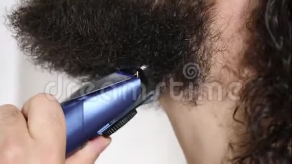 英俊的年轻人留着长发在浴室里用修剪器刮胡子特写镜头视频的预览图