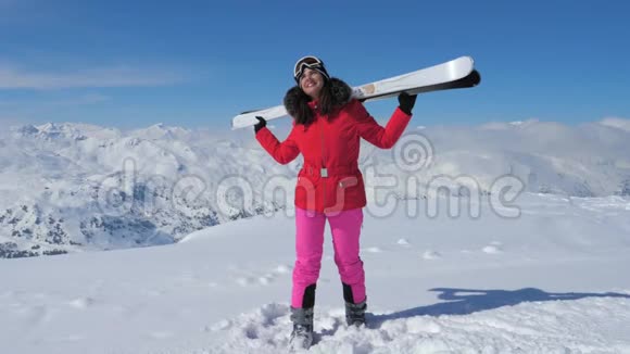 女子滑雪者站在斜坡山上双手扛着滑雪板视频的预览图
