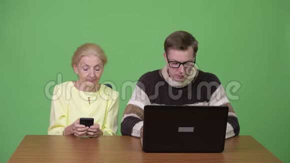 高级女商人用手机年轻帅哥用笔记本电脑视频的预览图