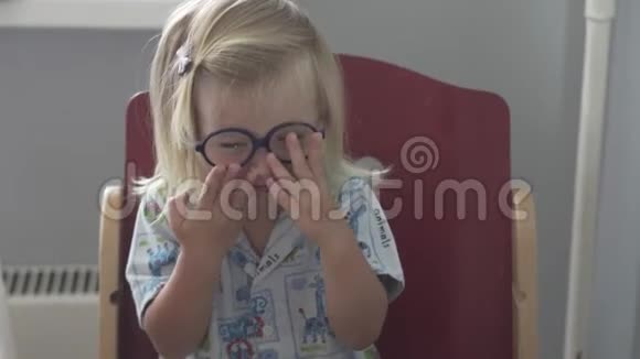 一个戴着眼镜和睡衣的小女孩正坐在厨房的桌子旁视频的预览图