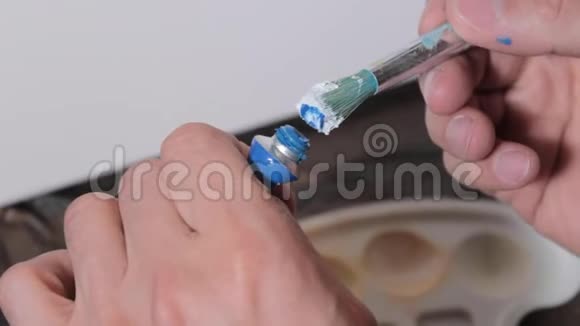 年轻的艺术家在画一幅画之前在画笔上画蓝色的画画家在画室视频的预览图