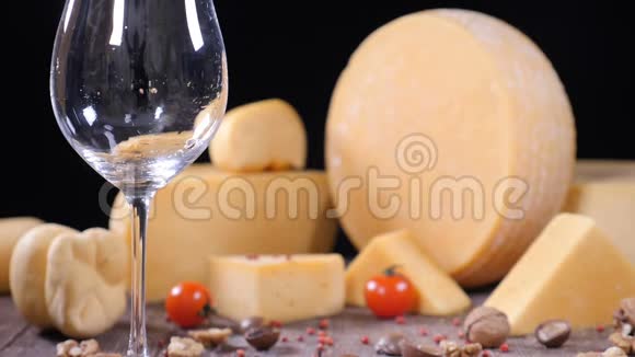 白葡萄酒被倒入一个杯子背景上有各种各样的硬奶酪食品艺术概念餐厅视频的预览图