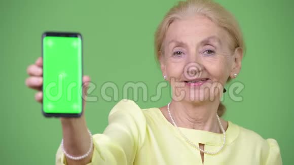 漂亮快乐的资深女商人一边展示手机一边微笑视频的预览图