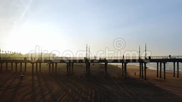 人们在黎明时沿着洪廷顿海滩码头散步空中飞行视频的预览图