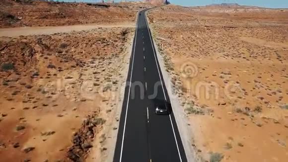 在亚利桑那空旷的沙漠公路上一名宇航员跟随着银色的汽车镜头倾斜以揭示平坦的景观和天际线视频的预览图