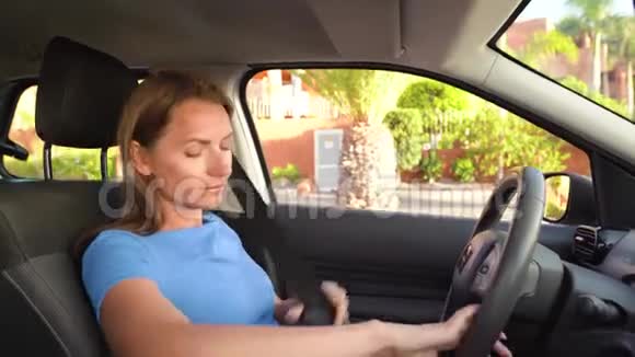 穿蓝色连衣裙的女士在开车前坐在车内系好安全带视频的预览图