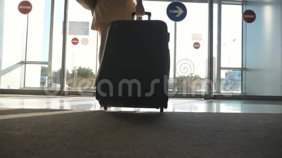穿高跟鞋的女人从机场出来用轮子滚动手提箱女孩带着手提箱沿着机场大厅走着视频的预览图
