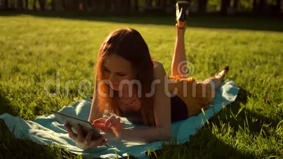 女性坐在公园的树上在平板电脑上使用互联网视频的预览图