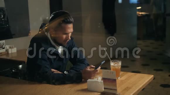 帅哥时尚男士通过语音识别留言在咖啡馆的智能手机上喝鸡尾酒视频的预览图