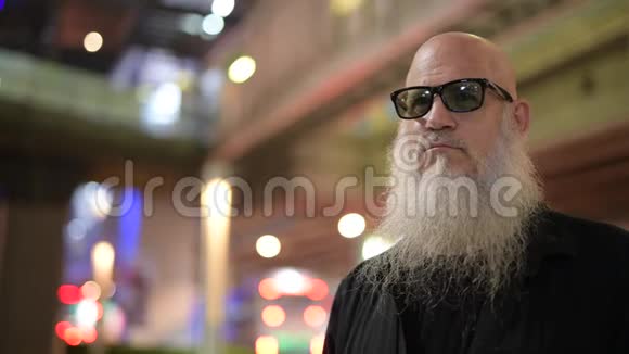 一个成熟的秃头游客晚上在城市的视野中等候视频的预览图