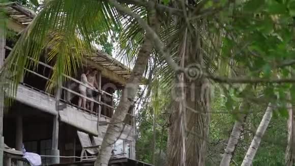 阳光普照的丛林别墅露台上的男人和女人视频的预览图