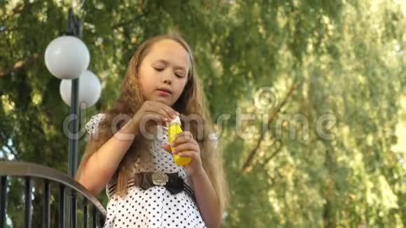 女孩在夏天的公园里膨胀肥皂泡和微笑视频的预览图