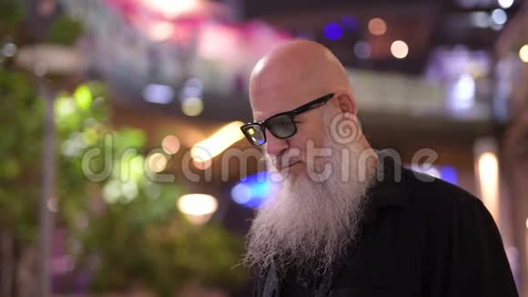 一个成熟的秃头游客晚上在城市的视野中等候视频的预览图