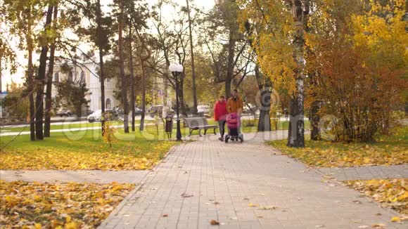 小孩子和他的父母在公园散步温暖的秋天下午视频的预览图