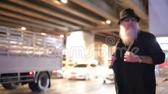 一个成熟的留胡子的游客晚上在路边等着视频的预览图
