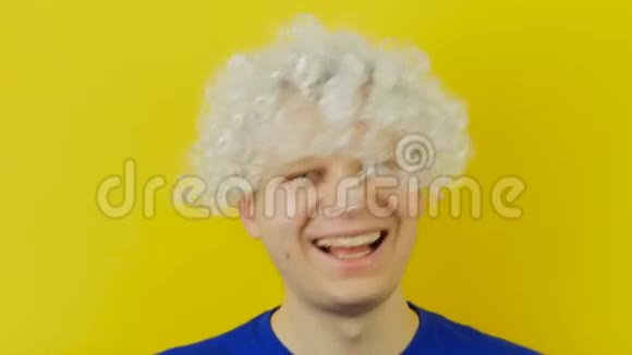 黄墙背景上有一幅年轻的卷发滑稽男子的肖像他留着白色的头发充满滑稽和欢乐的人类情感视频的预览图