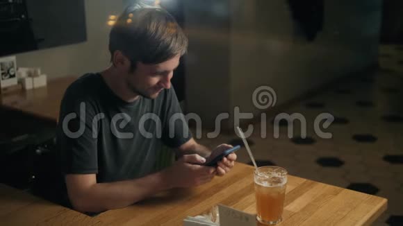帅哥时尚男士通过语音识别留言在咖啡馆的智能手机上喝鸡尾酒视频的预览图