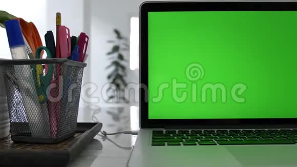 在客厅的办公桌上展示绿色彩色钥匙屏幕的笔记本电脑多利鞋视频的预览图