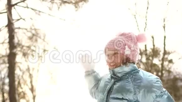 微笑的女孩在公园里享受寒冷阳光的早晨活泼的女学生在镜头前扔雪球视频的预览图