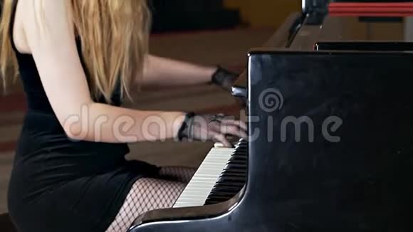 一个穿着黑色连衣裙脸上戴着面具的女孩弹钢琴不寻常的音乐表演视频的预览图