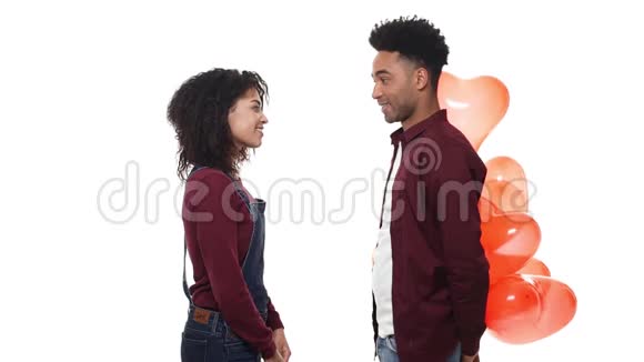 慢动作年轻英俊的非裔美国人惊喜他的女朋友与心脏气球在白色工作室背景视频的预览图