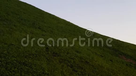 无人机飞过青山日落近景绿色草地视频的预览图