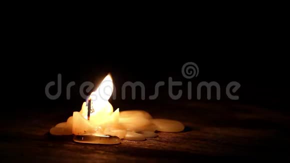美丽的燃烧蜡烛火焰从灯芯和蜡光进入黑暗的木桌背景与复制空间f视频的预览图