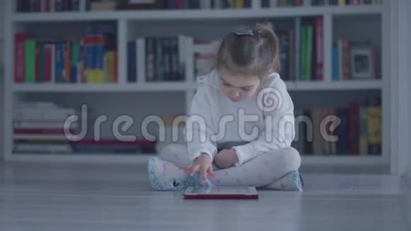 有兴趣的女孩带着平板电脑在地板上视频的预览图