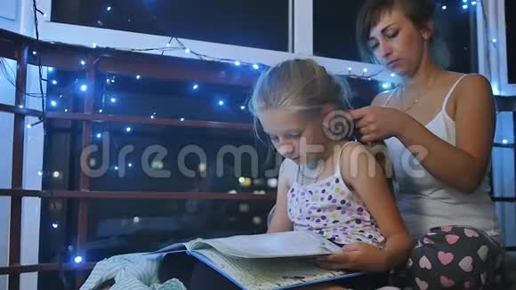 妈妈和女儿在睡觉前坐在夜窗附近女儿读了一本童话大书慢慢视频的预览图