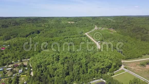 空中俯瞰郊区有许多绿色的树木和一条夏天天空下的道路剪辑森林中的小镇视频的预览图