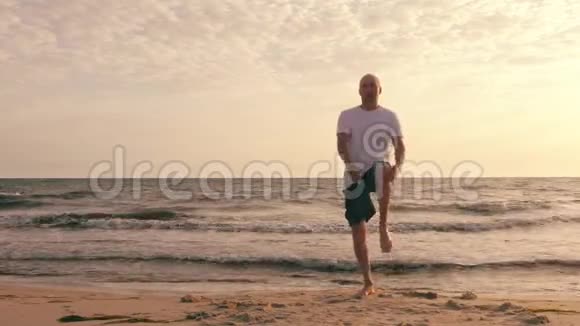 运动员在日落时分在海滩上锻炼和伸展双腿视频的预览图