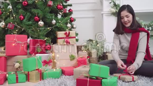 快乐的年轻亚洲女人在圣诞节的时候包装圣诞礼物装饰她家的客厅视频的预览图