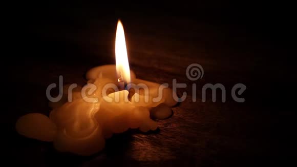美丽的燃烧蜡烛火焰从灯芯和蜡光进入黑暗的木桌背景与复制空间f视频的预览图