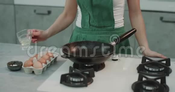 一个女孩把油放在平底锅里把她的鸡蛋调味到完美视频的预览图