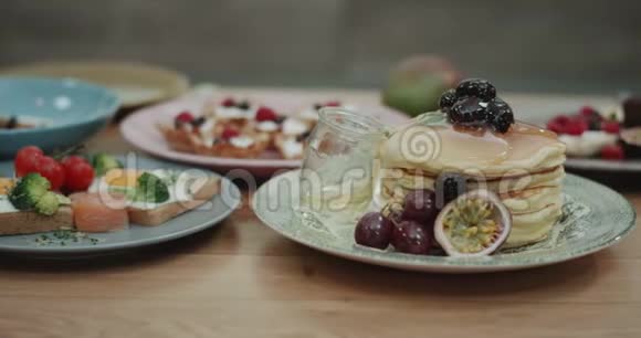 一杯美味的蜂蜜滴落在一叠煎饼和其他早餐食品旁边视频的预览图