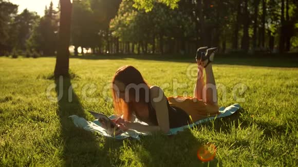 女孩坐在公园的树上用平板电脑上网视频的预览图