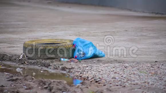 带有垃圾的蓝色垃圾袋靠近人行道旁边是一滩泥土和车轮上的橡胶轮胎视频的预览图