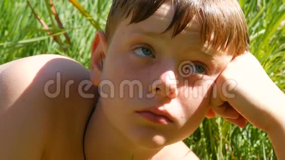 一幅可爱的红发少年的肖像夏天在绿草的背景下在河里游泳男孩视频的预览图