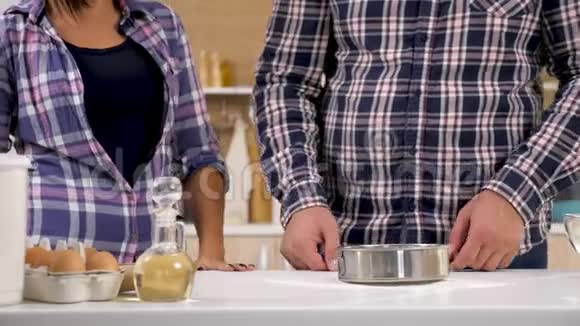 厨房里的一对夫妇用筛子筛面粉视频的预览图