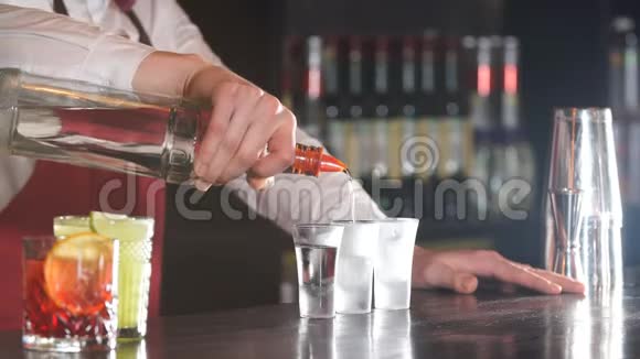 特写调酒师把一些饮料从瓶子里倒入木制柜台上的冷冻玻璃杯中视频的预览图